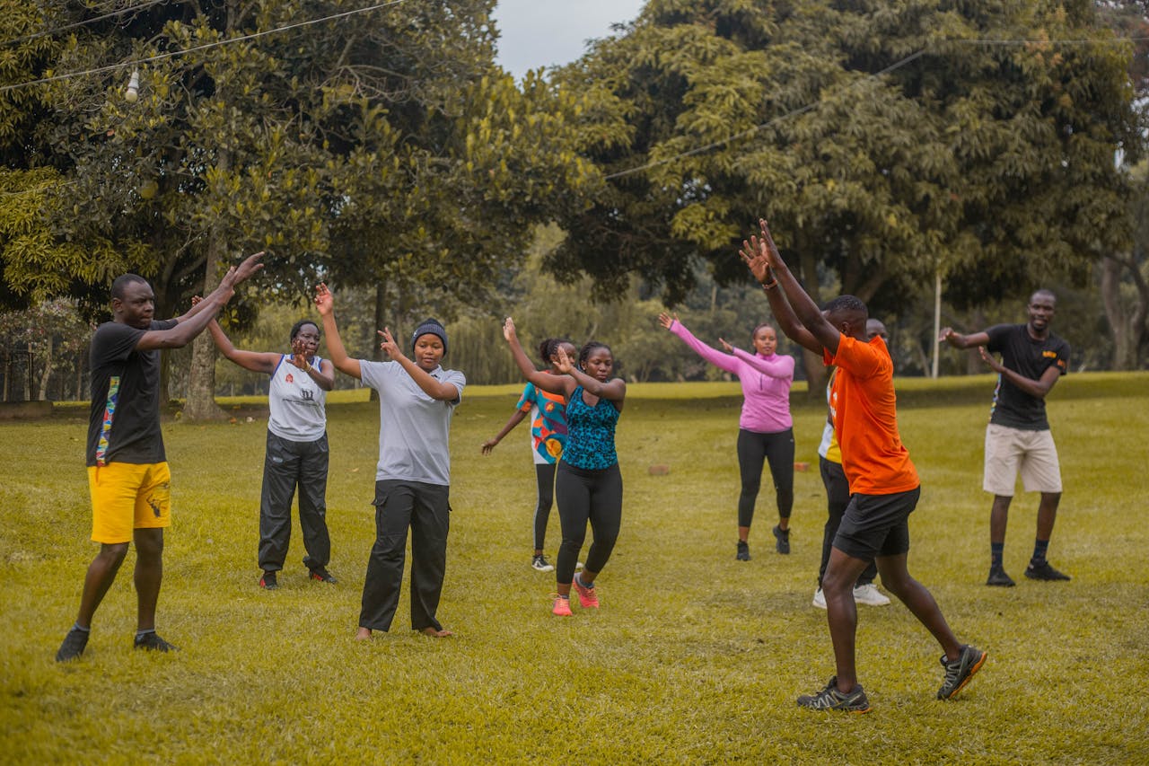 A lively group of adults participating in an outdoor fitness session on a sunny day in a park.